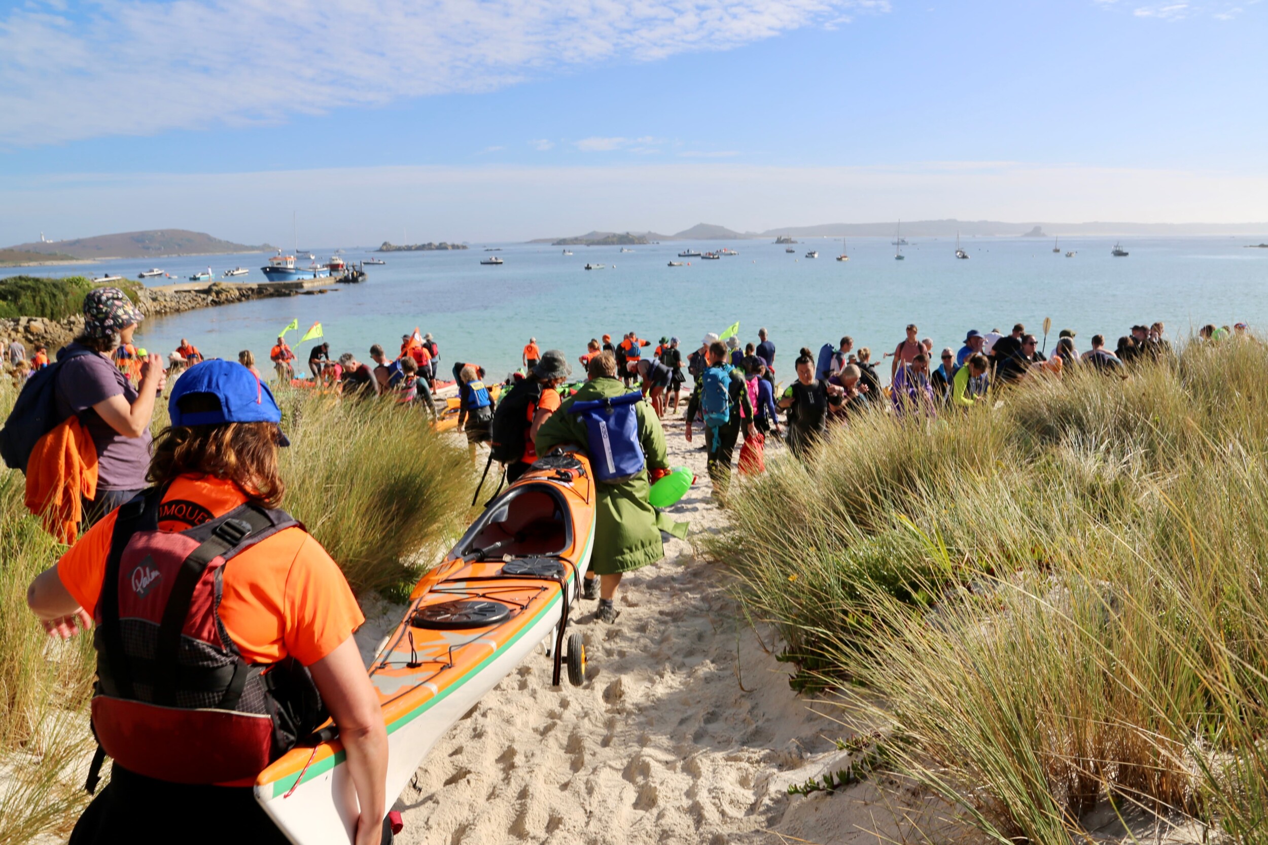 Kayakers and swimmer walk across the Isles of Scilly