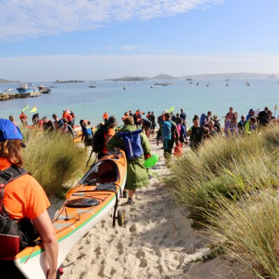 Kayakers and swimmer walk across the Isles of Scilly