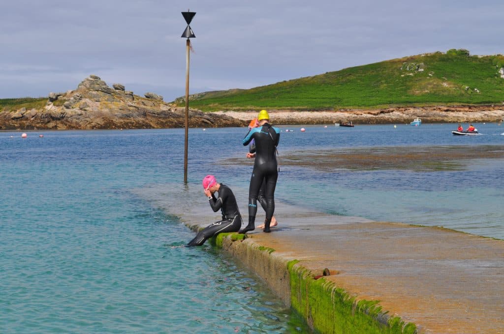 Swimmers entering the water in wetsuits on the Isles of Scilly St Marys