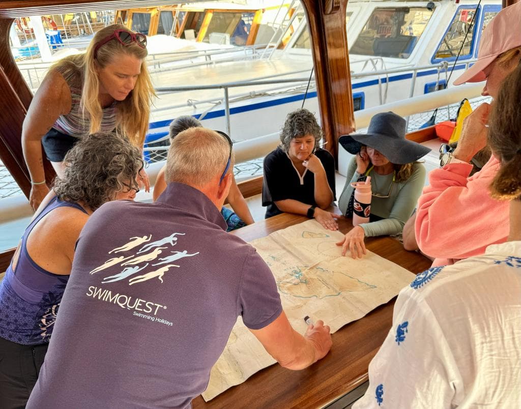 Group of people reviewing map around a table on a boat