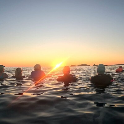 Swimmers hold hands and watch sunrise