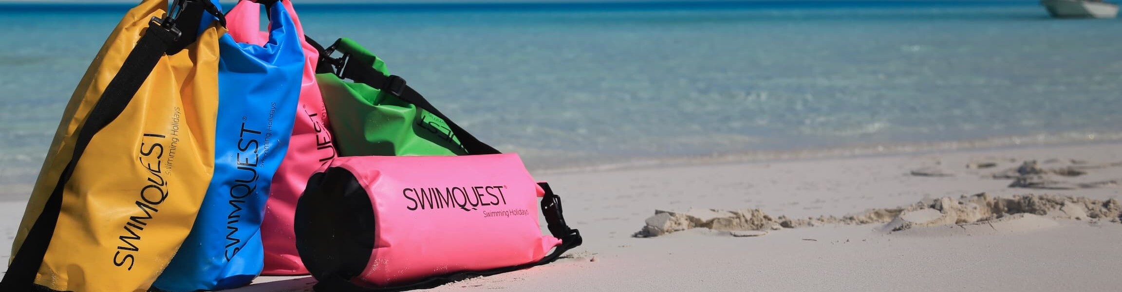 Colourful 10L dry bags on white beach