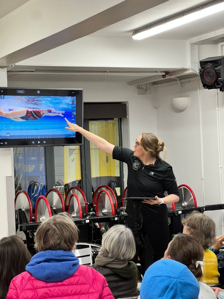 Cassie pointing at screen demonstrating front crawl