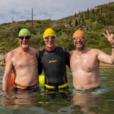 Three men standing in the sea after a swim