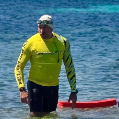 Man in yellow rash vest exits the sea