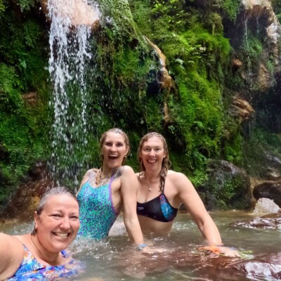 Three swimmers under a waterfall in the Azores
